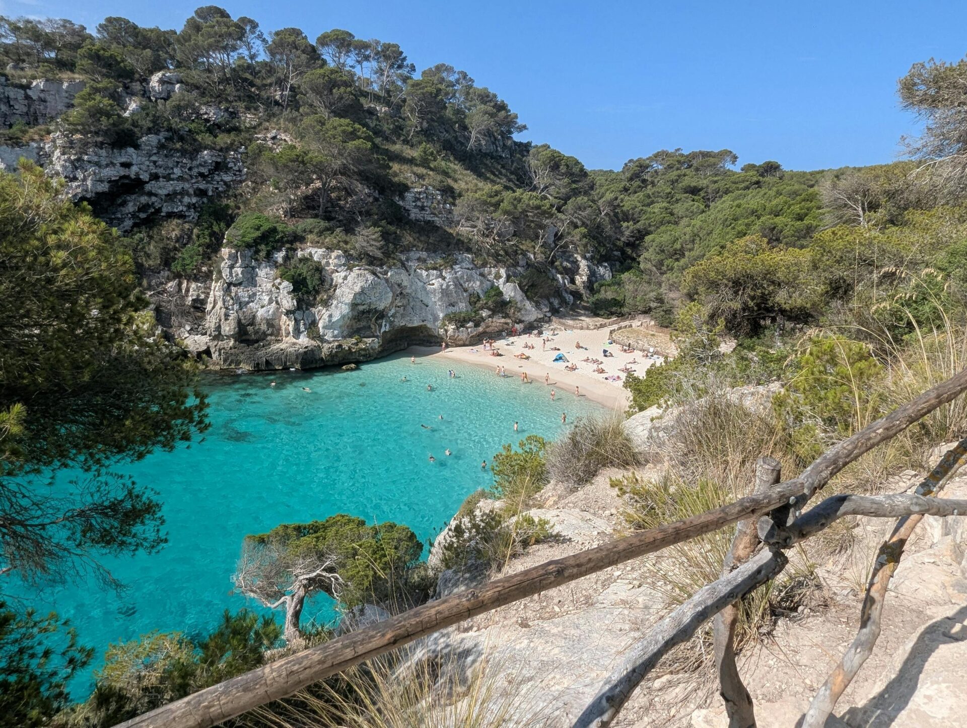 Idyllic beach scene at Cala Macarella, Ciutadella de Menorca, with turquoise water.
