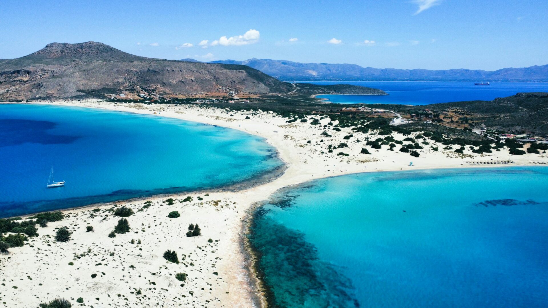 Stunning aerial view of Elafonissi Beach in Greece with crystal-clear turquoise waters and white sands.