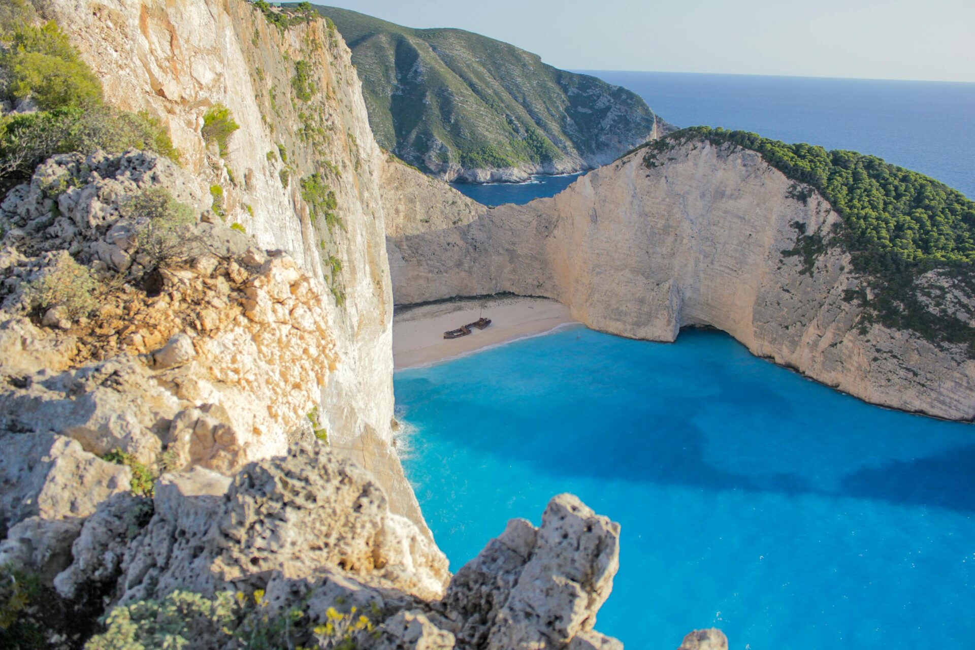 Stunning cliffside view of Navagio Beach's turquoise waters and sandy cove in Zakynthos, Greece.
