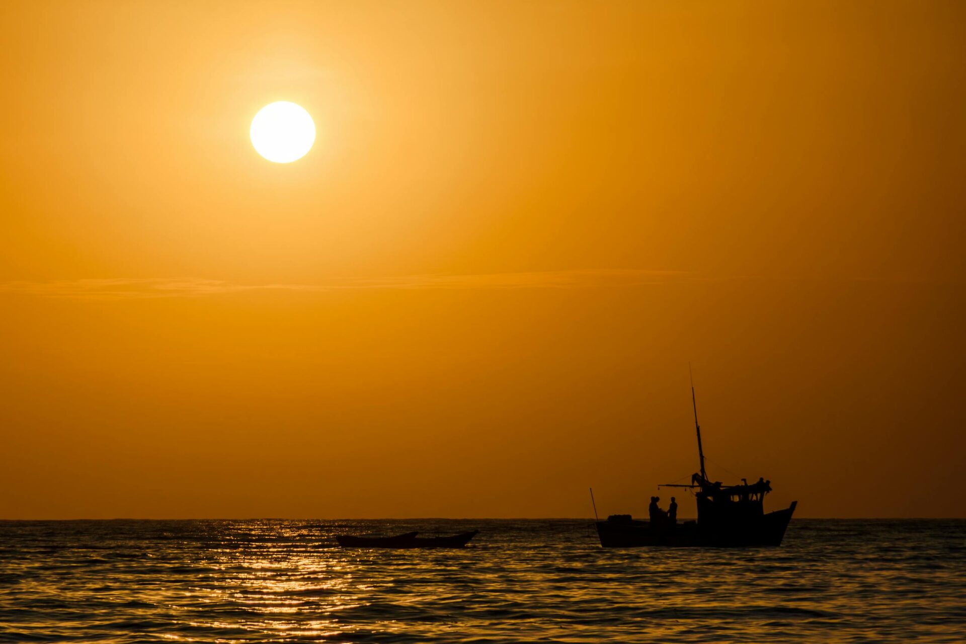 A stunning sunset view with a boat silhouette in Máncora, Peru. Vibrant and dramatic.