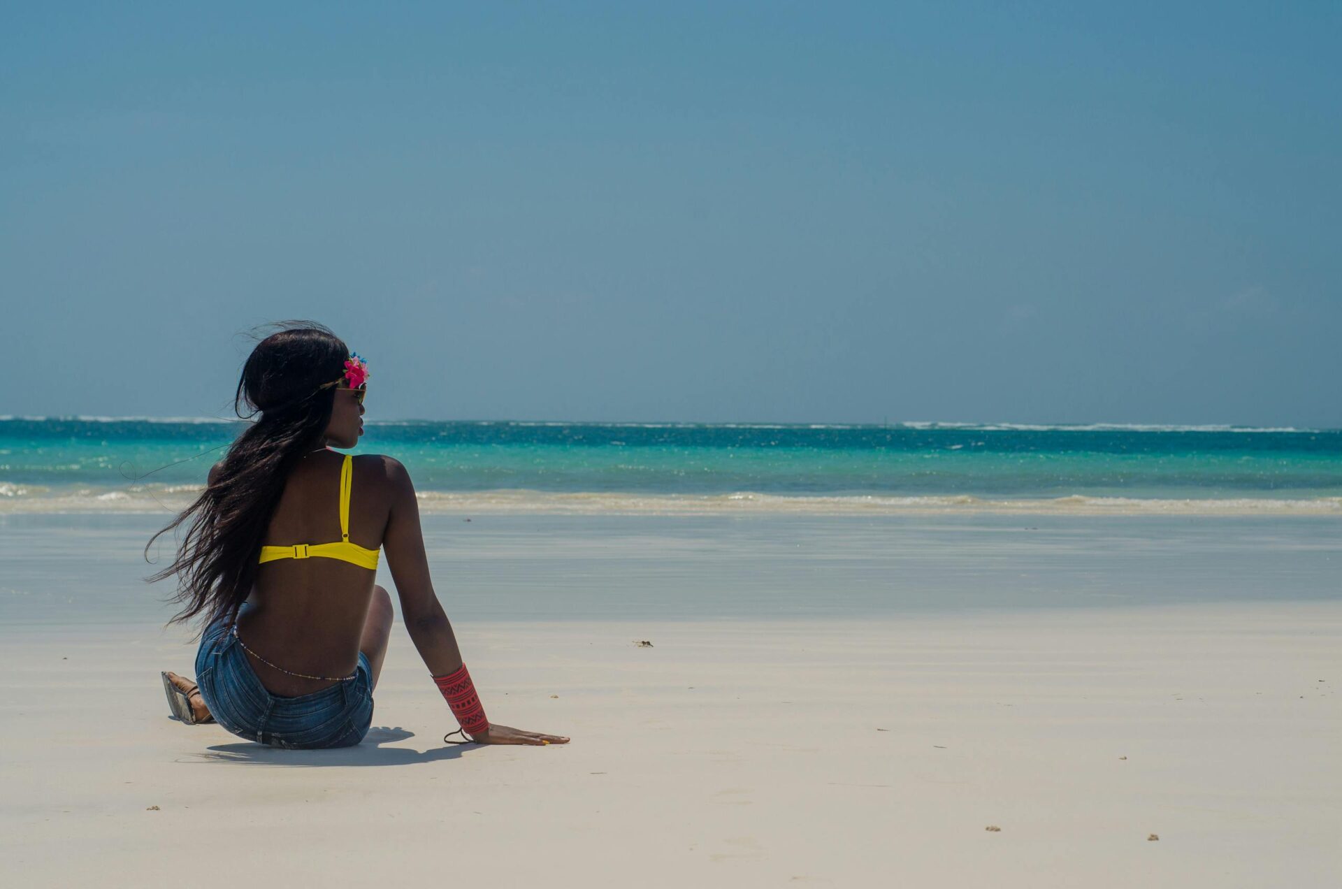 A woman enjoys a tranquil moment on Diani Beach, Kenya, gazing at the serene ocean.