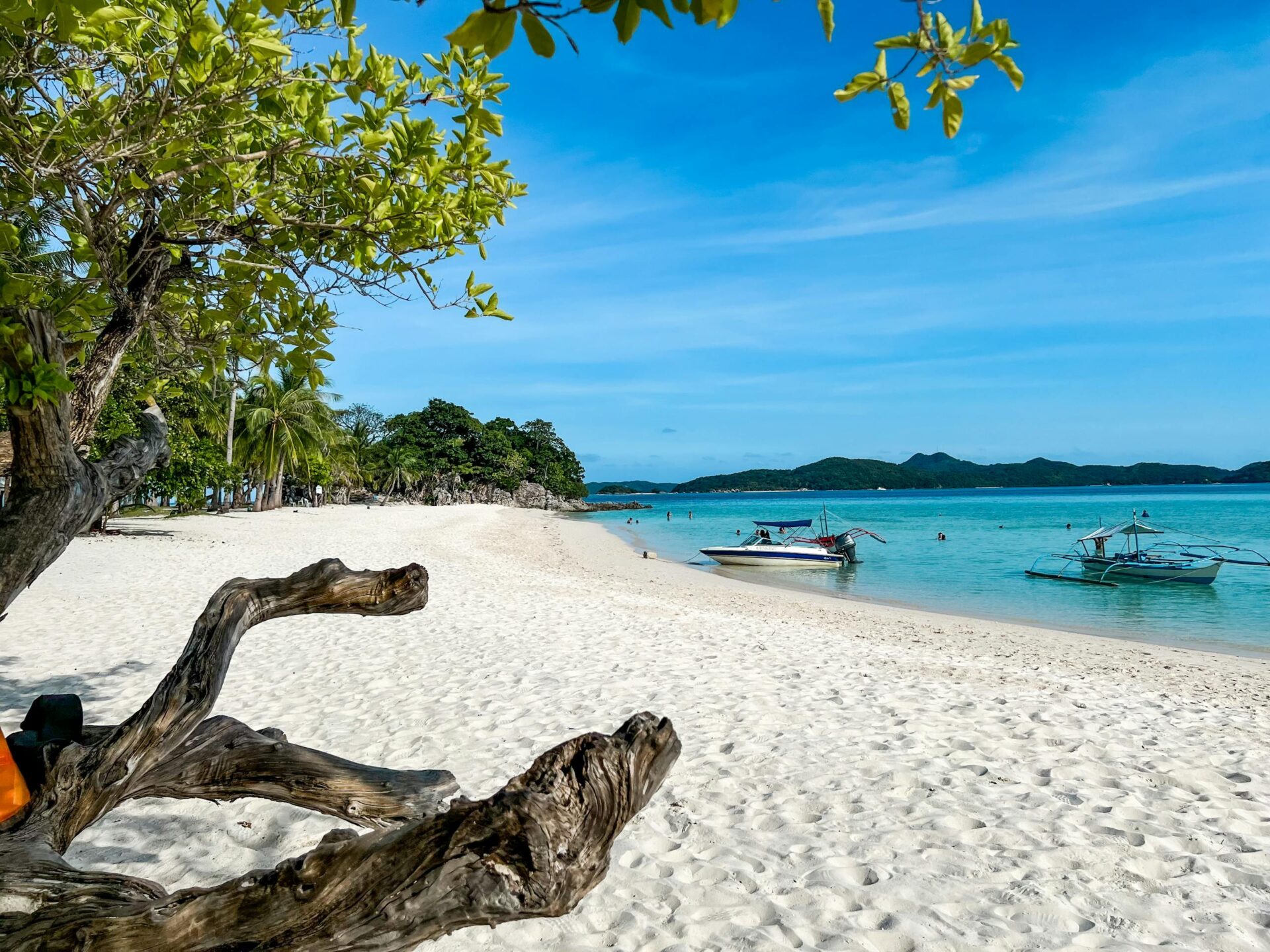 Beautiful sandy beach with boats and clear blue water in Palawan, Philippines.