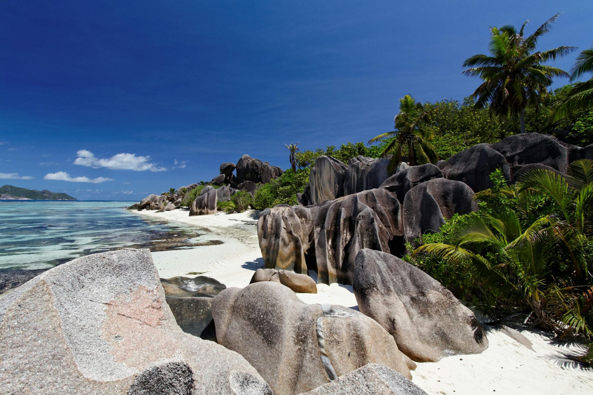 Breathtaking view of La Digue's granite rock formations and turquoise water under a clear blue sky.