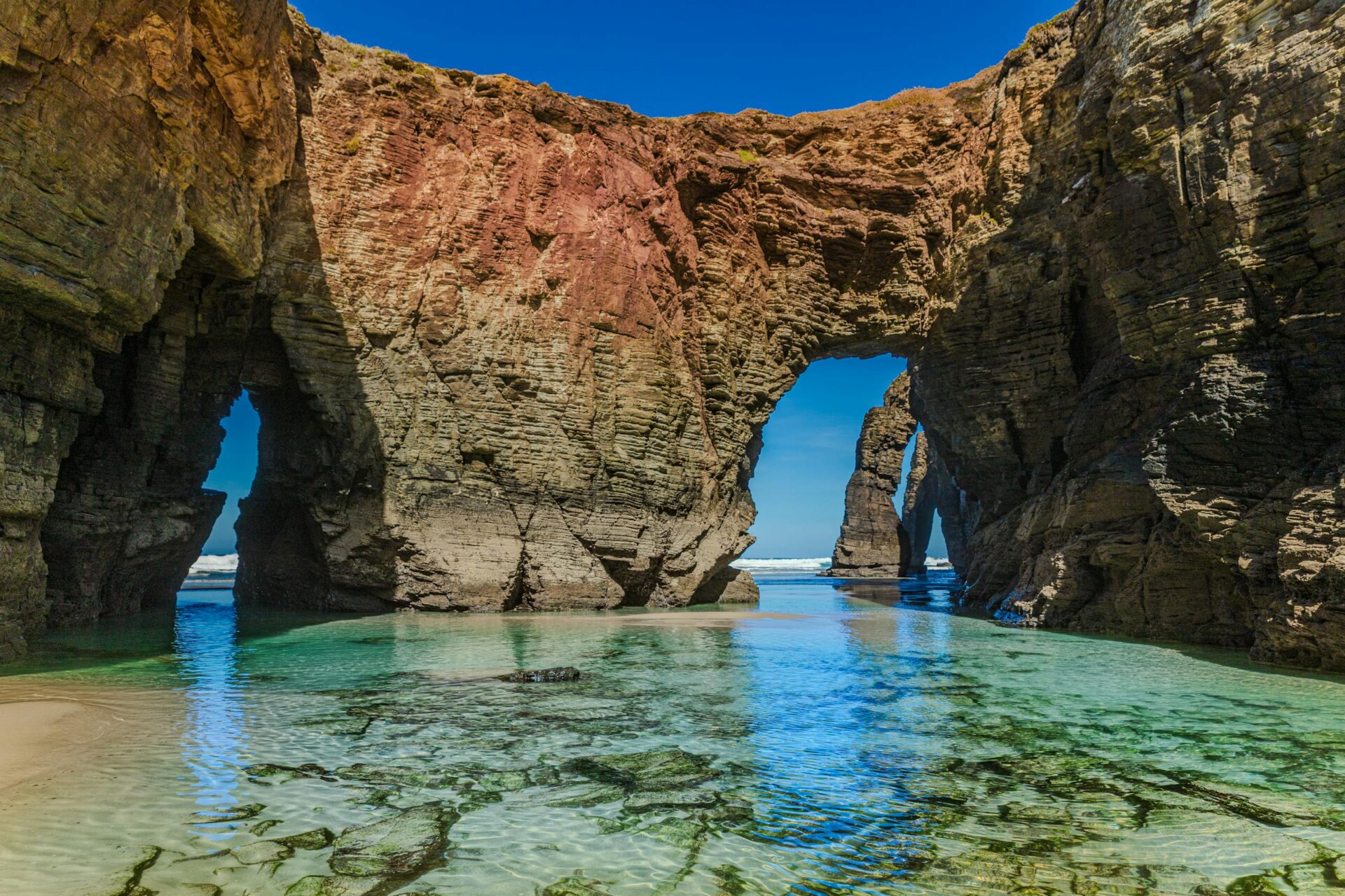 Dramatic rock formations and clear waters at A Rochela, a stunning beach in Spain.