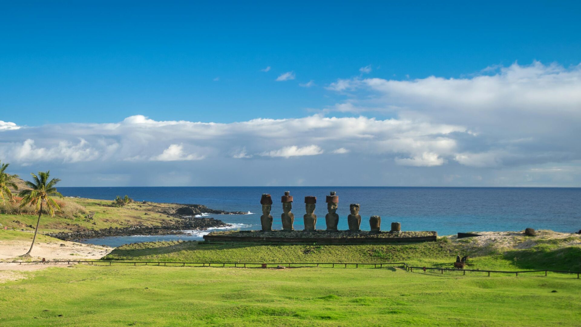 Iconic Moai statues at Ahu Tongariki under a clear blue sky on Easter Island's coast.