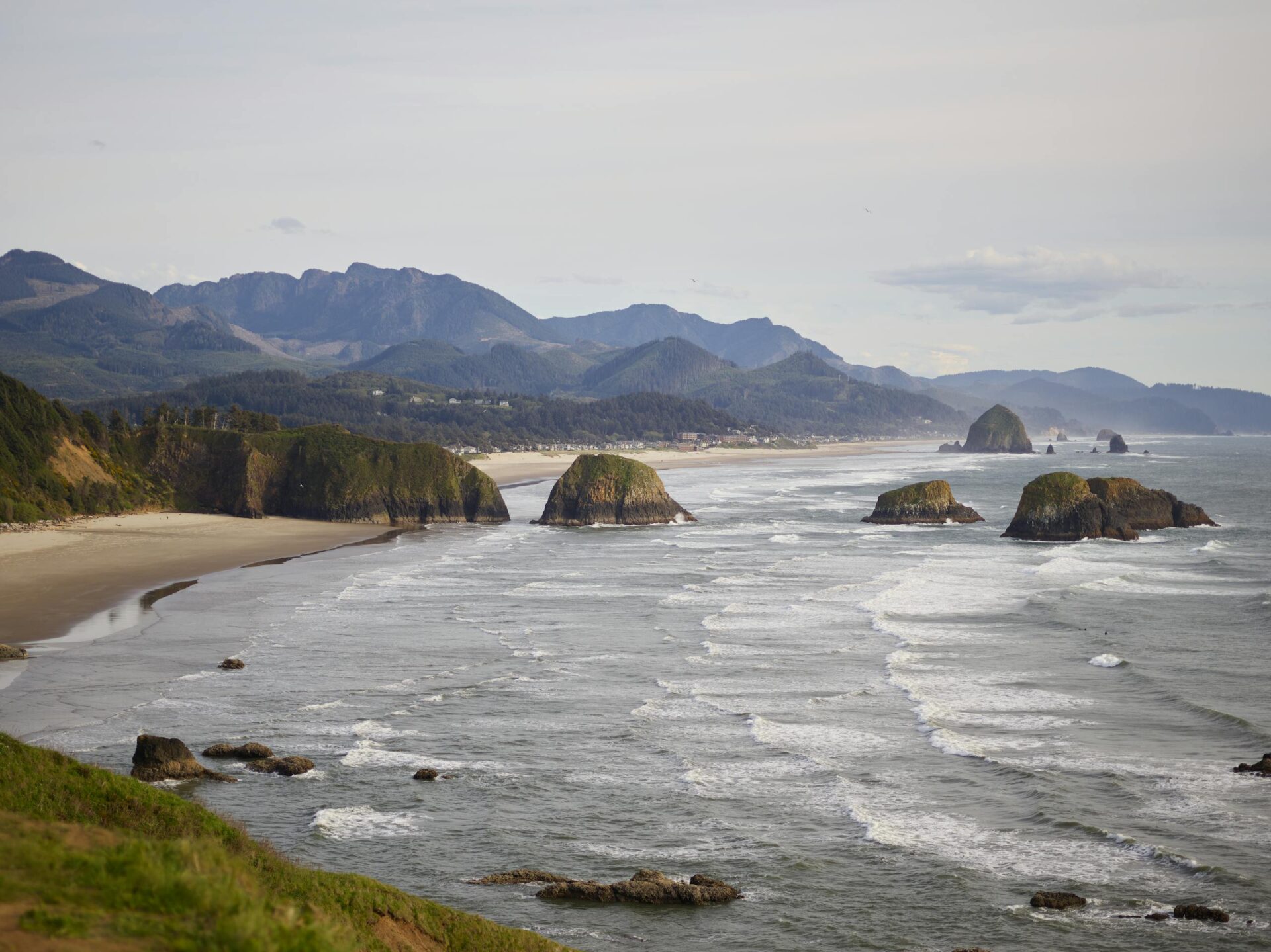 Picturesque view of rocky coastline of ocean against mountain ridges and sky during sunset