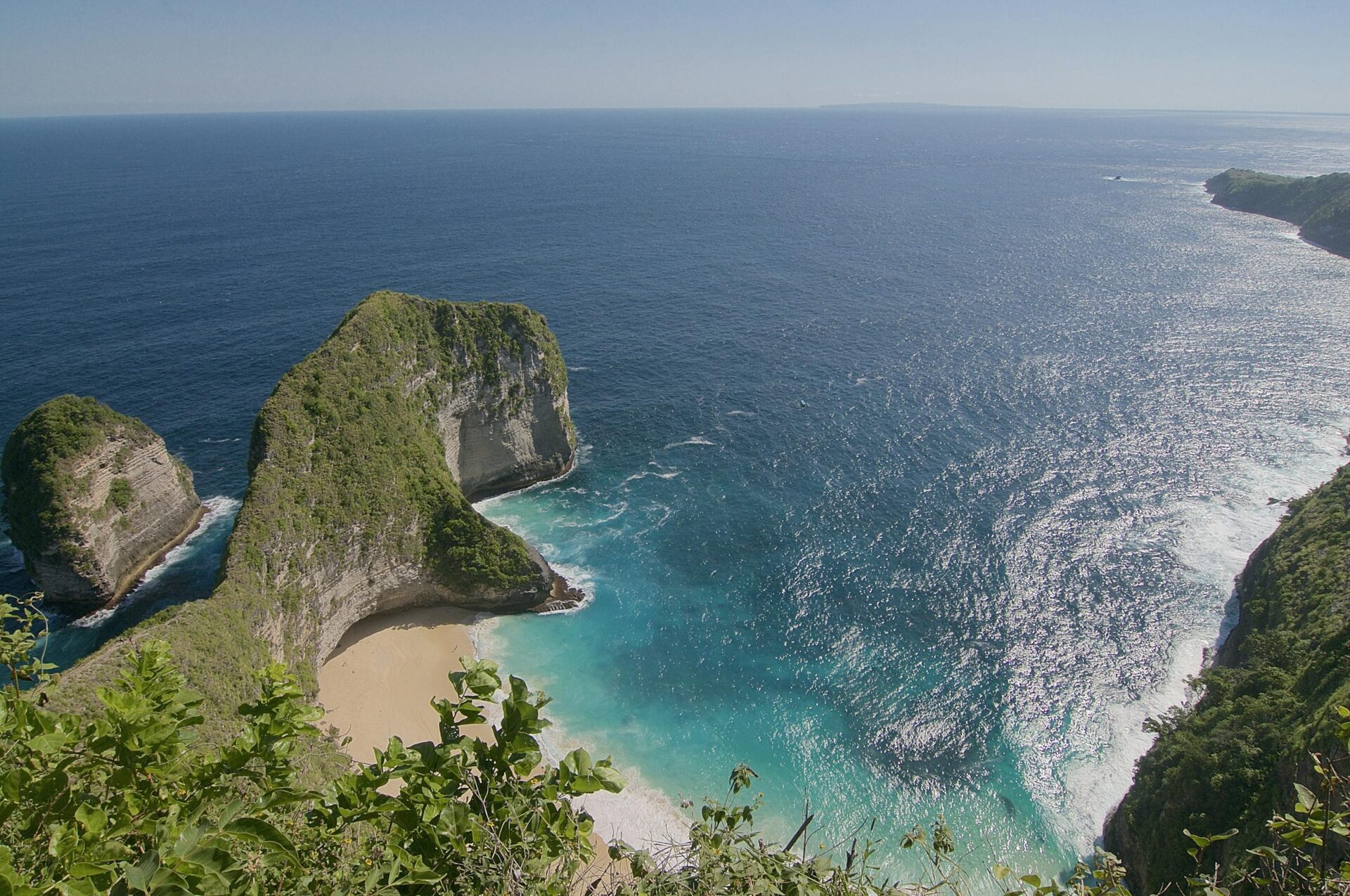 Stunning aerial view of Kelingking Beach, Bali, with turquoise waters and lush cliffs.