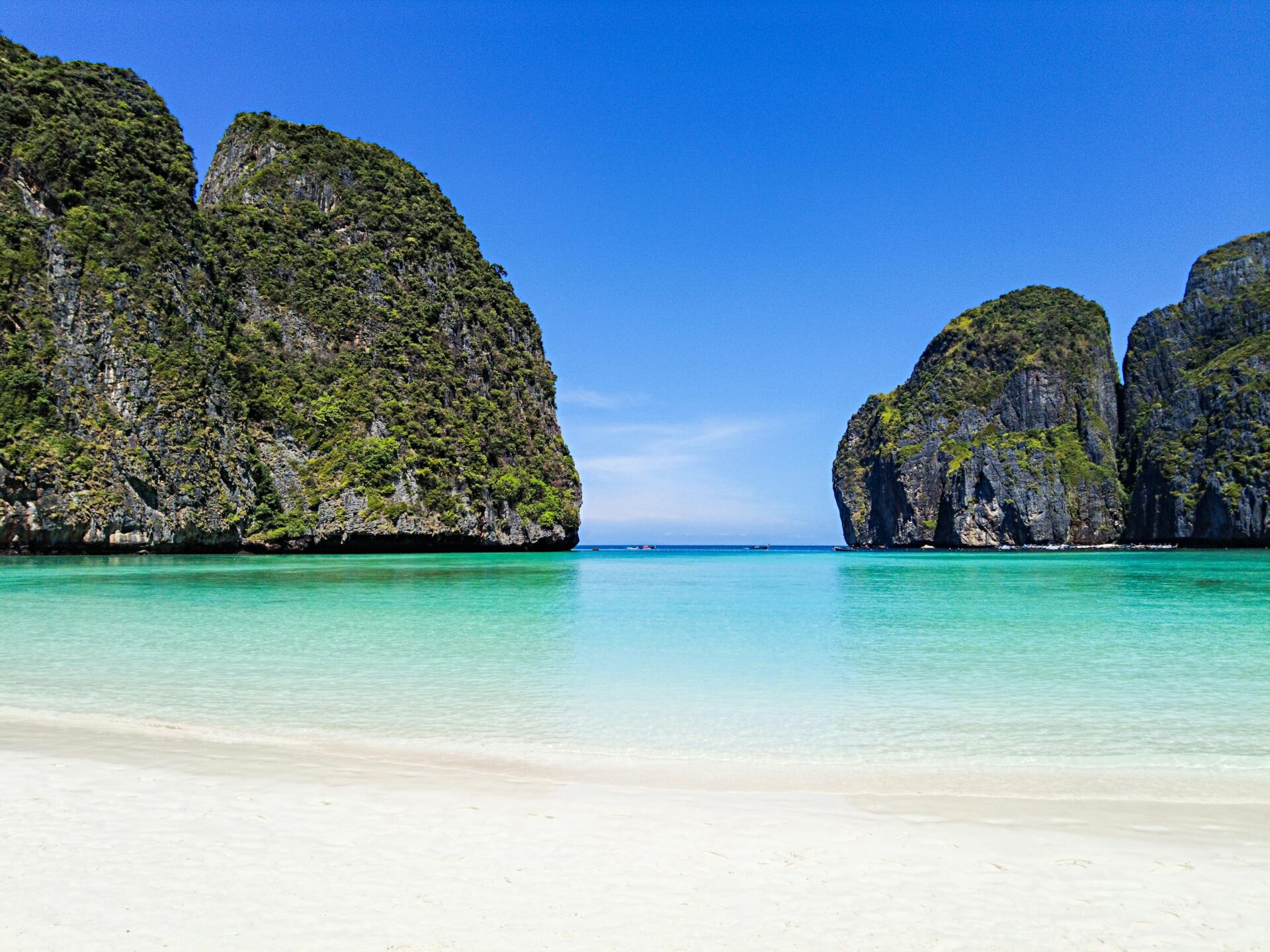 Stunning view of Maya Bay with turquoise water, white sand, and lush cliffs.
