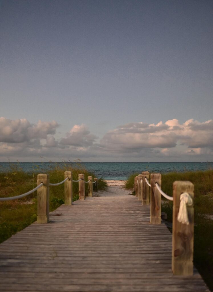 Tranquil footbridge leading to a stunning beach in Turks and Caicos, with a calm sea view.